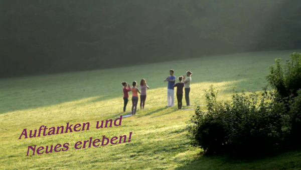 Six people doing yoga on a meadow far away. The photo sais